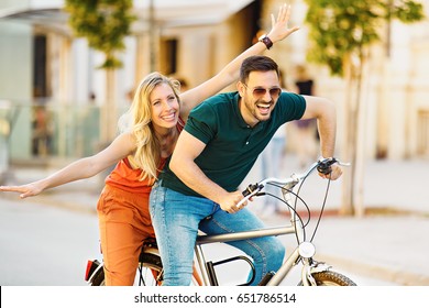 Portrait of happy young couple riding a bike in the city.