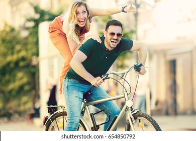 Portrait of happy young couple riding a bike in the city. - Shutterstock ID 654850792