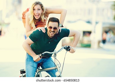 Portrait of happy young couple riding a bike in the city. - Shutterstock ID 654850813