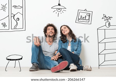 Portrait Of Happy Young Couple Sitting On Floor Looking Up While Dreaming Their New Home And Furnishing