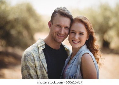 Portrait of happy young couple standing at olive farm on sunny day - Powered by Shutterstock