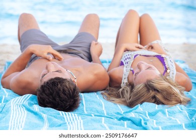  portrait happy young couple sunbathing on beach towels on the sand - Powered by Shutterstock