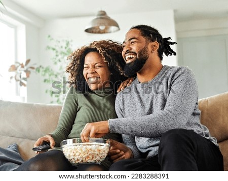 Portrait of a happy young couple watching tv together at home. Shot of a couple resting on the couch watching television