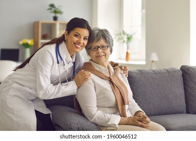 Portrait Of Happy Young Doctor Or Home Care Nurse Embracing Her Senior Patient. Retired Older Woman Together With Her Friendly General Practitioner Smiling And Looking At Camera