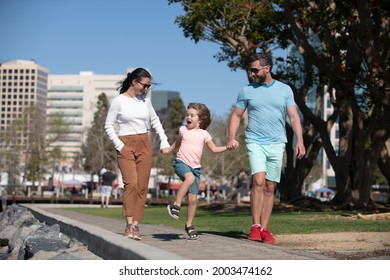 Portrait Of Happy Young Family Holding Hands Walking With Their Child On The City. People Urban Concept.