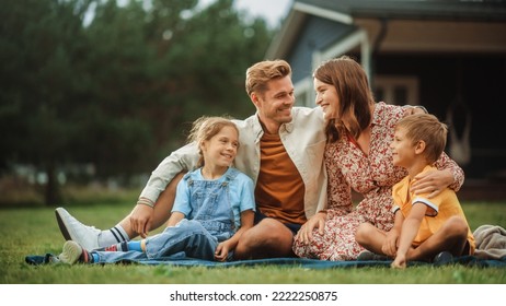 Portrait of a Happy Young Family with Kids Sitting on a Lawn in Their Front Yard on a Warm Summer Day at Home on a Picnic. Cheerful People Smile. - Powered by Shutterstock