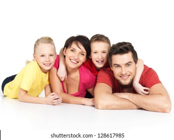 Portrait Of The Happy Young Family With Two Children Lying At Studio On White Floor