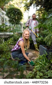 Portrait Of Happy Young Female Gardener With Colleague In Community Garden