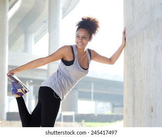 Portrait of a happy young fitness woman stretching outdoors - Shutterstock ID 245417497