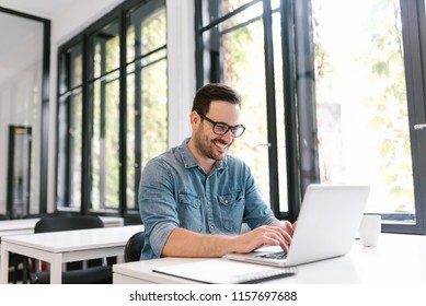 Portrait of happy young freelancer using laptop. - Shutterstock ID 1157697688