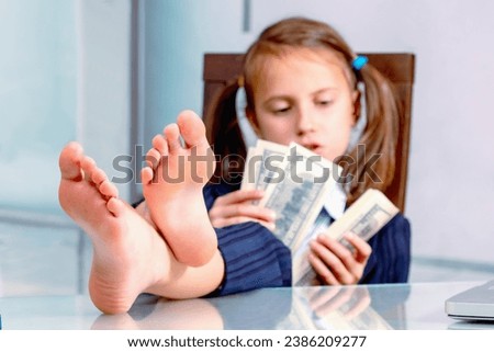 Portrait of happy young girl counts money profit. Selective focus on bare feet