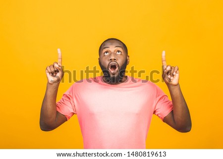 Portrait of happy young good-looking afro american man with in casual smiling, pointing aside with finger, looking in camera with excited face expression