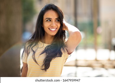 Portrait Happy Young Hispanic Woman Smiling With Hand In Hair And Looking Away 