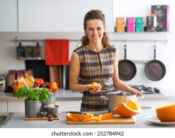 Portrait of happy young housewife cooking pumpkin
