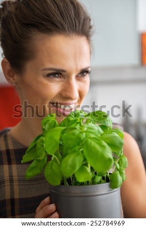 Portrait of happy young housewife with fresh basil