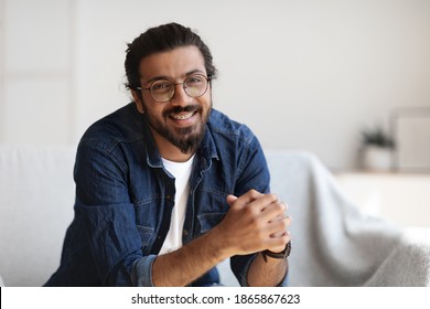 Portrait Of Happy Young Indian Man With Eyeglasses And Dental Braces Posing In Home Interior, Handsome Millennial Western Guy With Beard Smiling At Camera While Relaxing In Living Room, Free Space