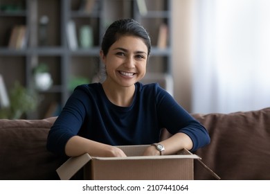 Portrait Of Happy Young Indian Woman Sitting On Sofa With Cardboard Box, Unpacking Parcel With Order From Internet Store, Satisfied With Fast Delivery Service, Client Has Positive Shopping Experience.