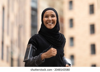 Portrait Of Happy Young Islamic Lady In Hijab Jogging Outdoors, Motivated Athletic Muslim Woman Wearing Modest Sportswear Training On City Streets, Enjoying Running, Closeup Shot, Free Space