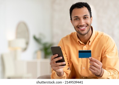 Portrait of happy young male client using card to order and buy goods online at web store via special app. Smiling millennial man shopping online in internet, posing looking at camera, free copy space - Powered by Shutterstock