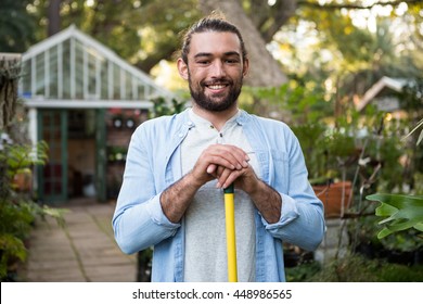Portrait of happy young male gardener with work tool at garden - Shutterstock ID 448986565