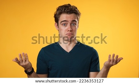 Portrait of happy young man 20s shrugging shoulders and gesturing I do not know isolated on yellow background.