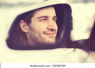 Portrait Happy Young Man Driver Reflection In Car Side View Mirror. Guy Driving His New Car. Positive Human Face Expression Emotions. Safe Trip Journey Driving Concept