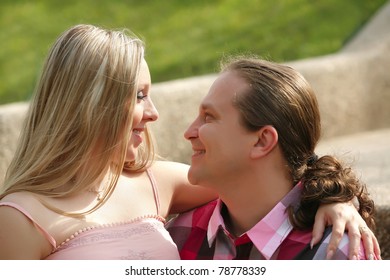 Retrato de un joven feliz mirando a su esposa embarazada. al aire libre.