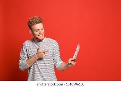 Portrait Of Happy Young Man With Lottery Ticket On Red Background