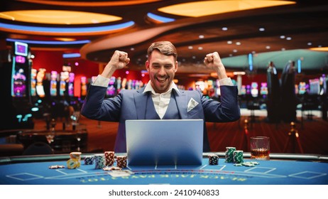 Portrait of a Happy Young Man in a Suit Using a Laptop Computer in Casino. Lucky Businessman Celebrating and Cheering Blackjack Jackpot Win in Online Game on Betting Online Casino Website. - Powered by Shutterstock