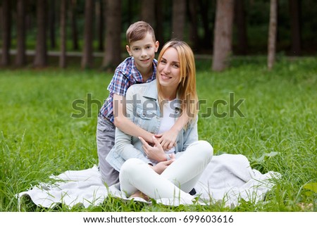Portrait of happy young mother with her son having fun together. kissing and Embrace outdoors