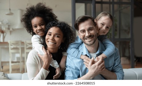Portrait of happy young multiethnic family with small diverse daughters relax in living room at home. Smiling multiracial mom and dad cuddle hug with adopted small girls children. Adoption concept. - Shutterstock ID 2264508015