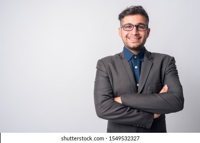 Portrait of happy young Persian businessman in suit smiling with arms crossed - Shutterstock ID 1549532327