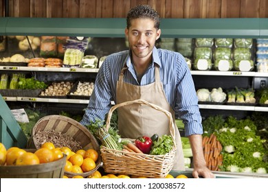 Portrait of a happy young salesman with vegetable basket in supermarket - Powered by Shutterstock