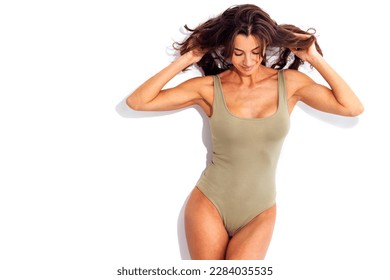 Portrait of happy young slim beautiful smiling woman in green  swimsuit. Studio shot of pretty caucasian brunette female on white background. Isolated. Free space for text.