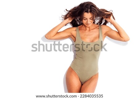 Portrait of happy young slim beautiful smiling woman in green  swimsuit. Studio shot of pretty caucasian brunette female on white background. Isolated. Free space for text.