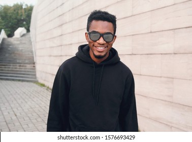 Portrait happy young smiling african man wearing black hoodie, sunglasses on city street - Powered by Shutterstock
