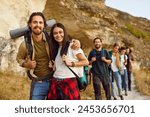 Portrait of a happy young smiling joyful friends tourists looking cheerful at camera standing outdoor and having walking tour of the mountains. Hiking, adventure and people travel concept.