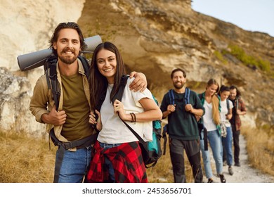 Portrait of a happy young smiling joyful friends tourists looking cheerful at camera standing outdoor and having walking tour of the mountains. Hiking, adventure and people travel concept. - Powered by Shutterstock