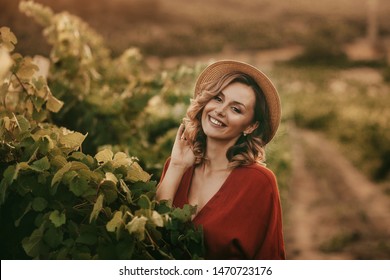 portrait of a happy young woman 30-32 years old in the summer vineyards at sunset. woman in a hat and smiling - Powered by Shutterstock