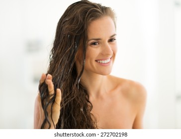 Portrait Of Happy Young Woman Applying Hair Mask In Bathroom