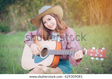 portrait of a happy young woman asia playing guitar outdoors
