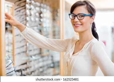 Portrait of happy young woman buying new glasses at optician store