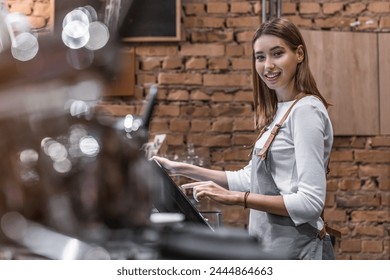 Portrait of happy young woman at counter with cashbox working in coffee shop cafe restaurant looking at camera. Caucasian waitress in apron using finger touching screen of POS terminal in coffee shop - Powered by Shutterstock