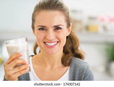 Portrait of happy young woman drinking smoothie in kitchen - Powered by Shutterstock