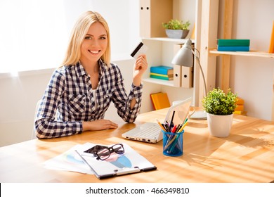 Portrait of happy young woman holding bank card and doing internet shopping