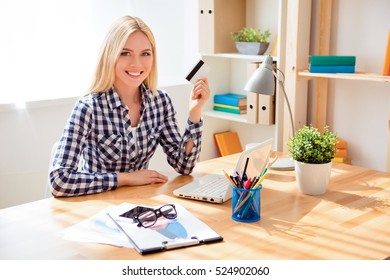 Portrait of happy young woman holding bank card and doing internet shopping.