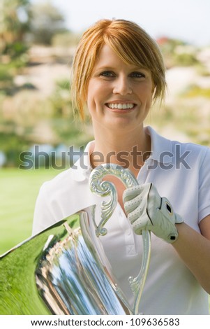 Portrait of a happy young woman holding trophy after winning