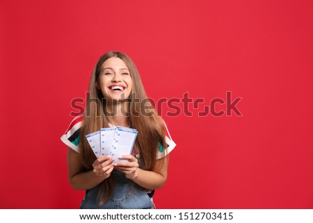 Portrait of happy young woman with lottery tickets on red background