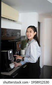 Portrait of happy young woman office worker making coffee from coffee machine in the office.