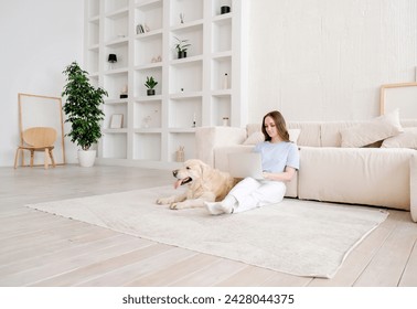 Portrait of happy young woman with pet dog, sitting on floor at home. Caucasian female hugging golden retriever in living room - Powered by Shutterstock